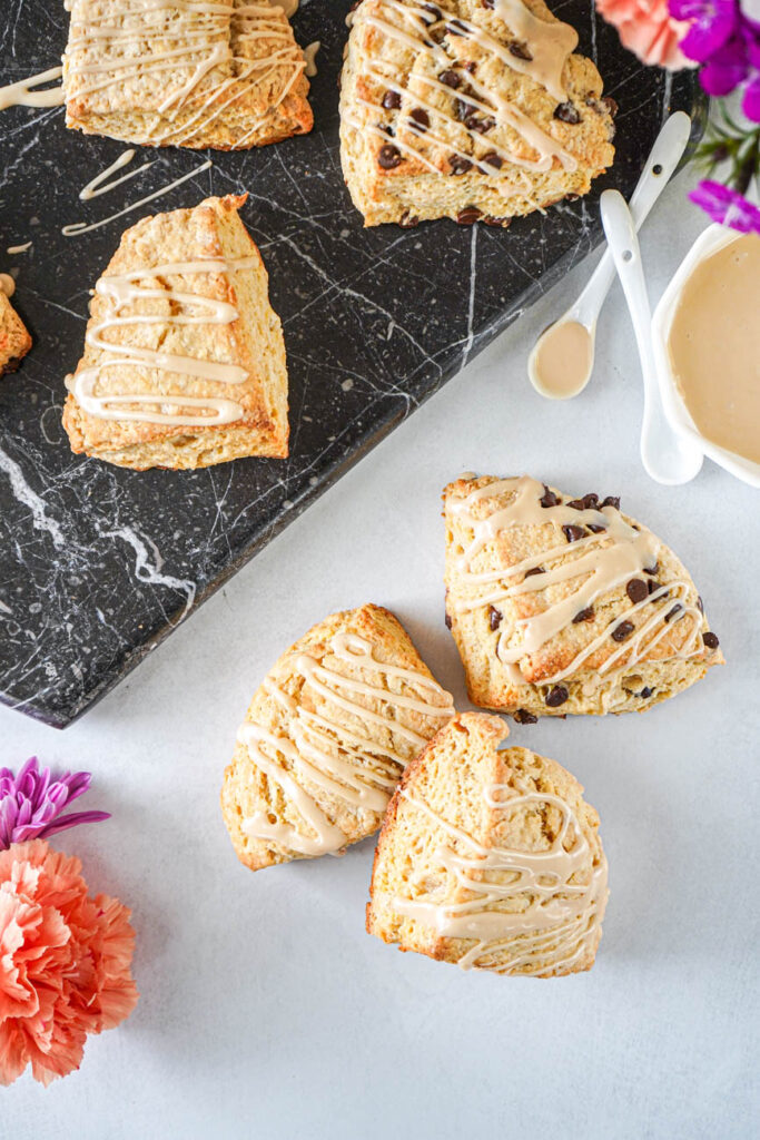 Aerial view of Irish Cream Scones next to a bowl of Irish cream glaze and two white spoons.