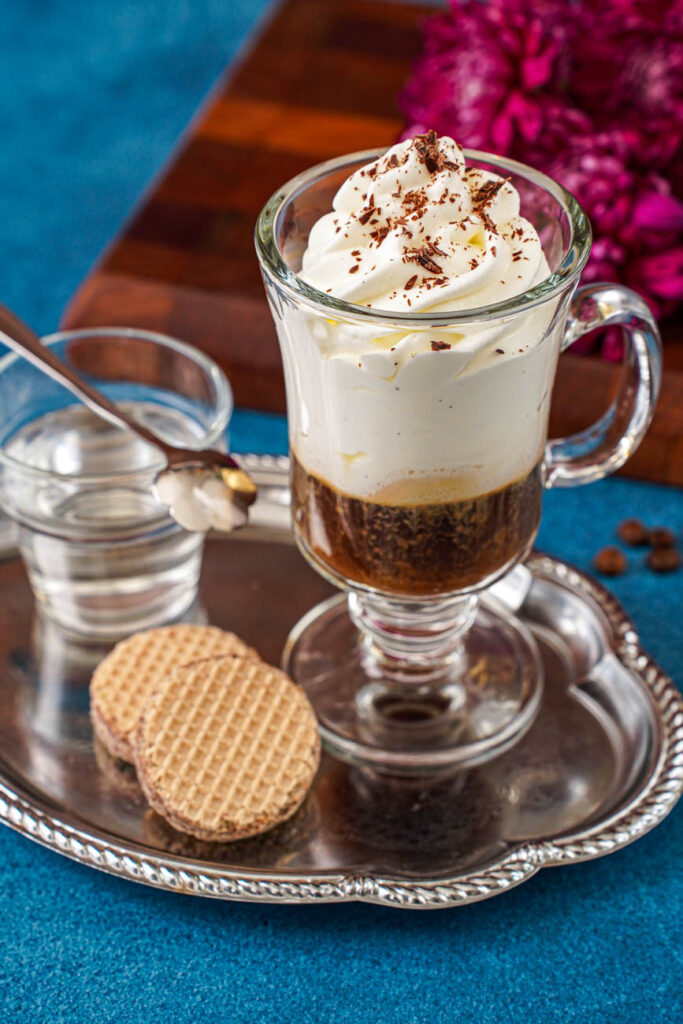 Close up of Einspänner (Viennese Coffee with Whipped Cream) on a tray with chocolate flakes over the top.