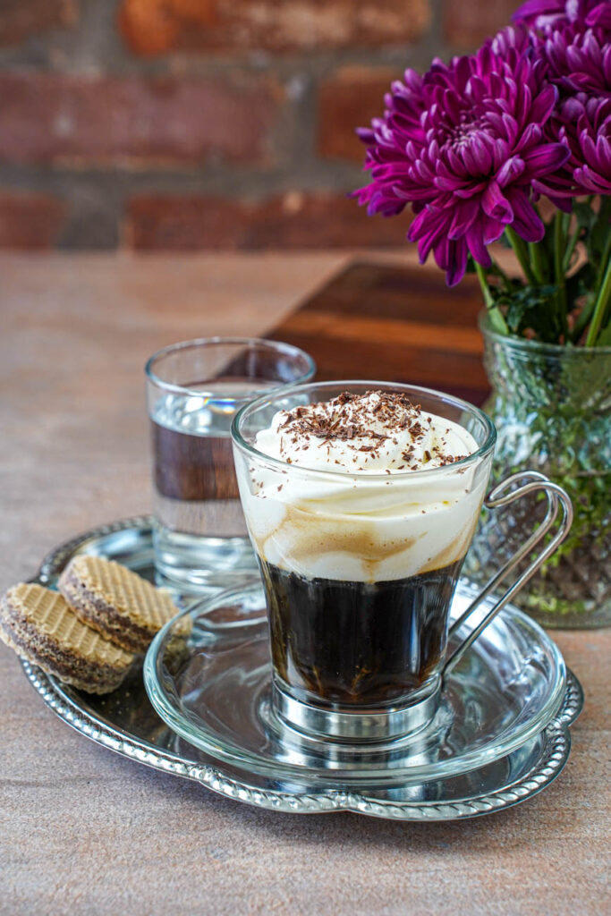 Einspänner (Viennese Coffee with Whipped Cream) in a small glass on a tray.