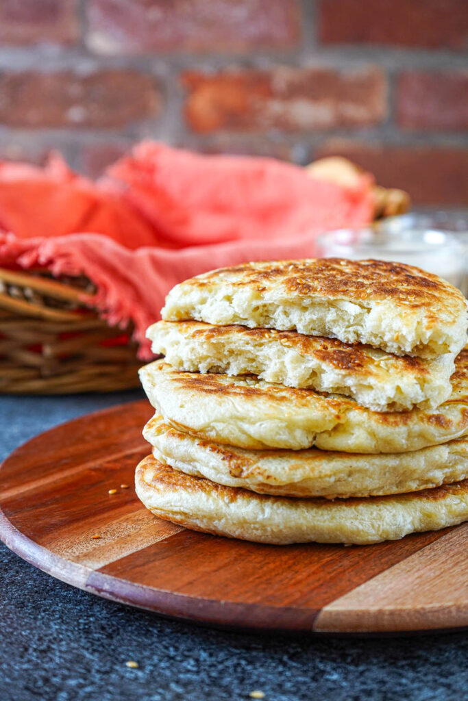 A stack of Mkatra Foutra (Sesame Coconut Flatbreads) with the top torn in half.
