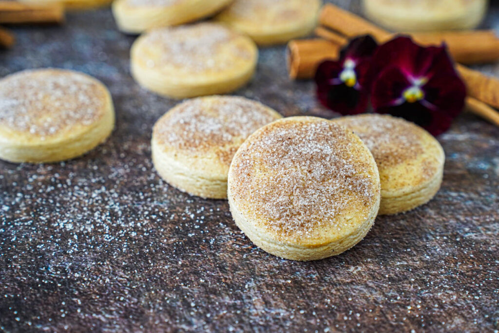 Biscotti Diamante covered in cinnamon sugar and next to red pansies and cinnamon sticks.