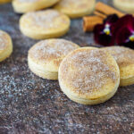 Biscotti Diamante covered in cinnamon sugar next to red pansies and cinnamon sticks.
