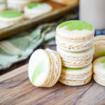A stack of Irish Cream Macarons with more in the background on a baking sheet.