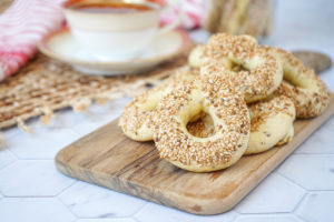 Kaak (Cookies with a Sesame-Anise Glaze) on a wooden board with teacup in background.