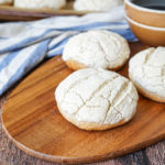 Three Semitas de Yema on a wooden board with a coffee cup.