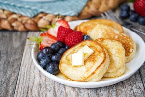 Four Silver Dollar Pancakes on a white plate with fresh berries.