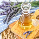 Homemade Lavender syrup in a jar on a wooden board next to fresh lavender.