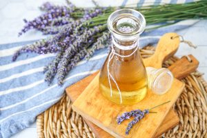 Homemade Lavender syrup in a jar on a wooden board next to fresh lavender.
