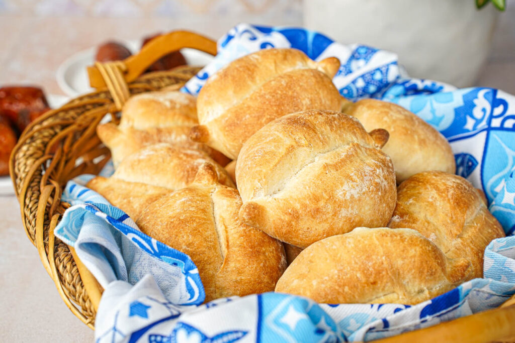 Papo Secos (Crusty Rolls) in a basket with a blue and white towel.