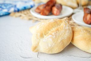 Papo Secos (Portuguese Crusty Rolls) with grilled sausage in the background.