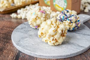 Three popcorn balls on a marble slab.