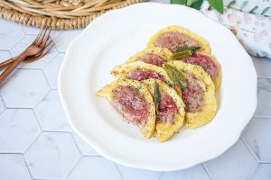 Casunziei All'Ampezzana (Beet Filled Pasta with Poppy Seeds) on a white plate topped with sage.