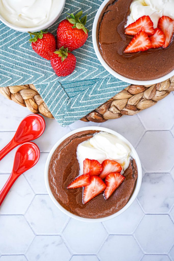 Spiced Cacao Manna Porridge Aerial view of Spiced Cacao Manna Porridge in two white bowls with strawberries and creme fraiche.