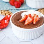 Spiced Cacao Manna Porridge in a white ramekin with cream and strawberries.