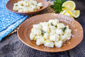Gnocchi al Limone (Lemon Gnocchi) on two brown plates next to lemons and mint.