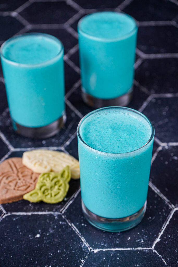 Close up of Galaxy's Edge Inspired Blue Milk in three glasses next to cookies.