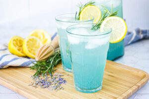 Lavender Lemonade in two glasses garnished with lemon slices and rosemary.