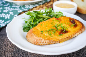 Welsh Rarebit (Welsh Cheese Toast) on a white plate next to arugula.