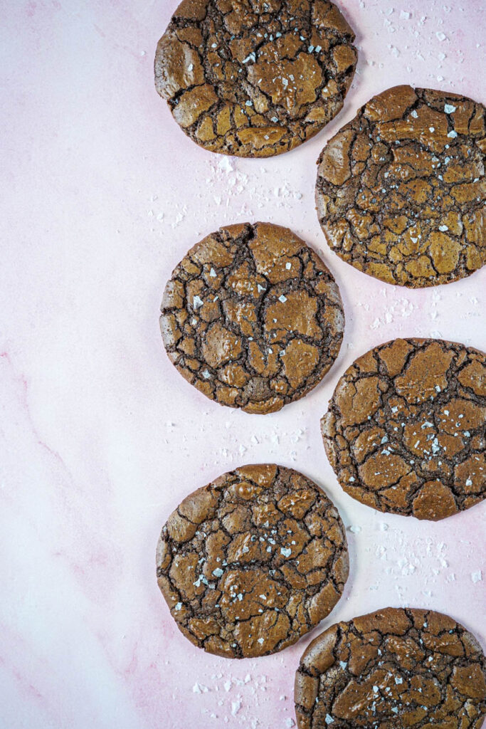 Aerial view of Crinkly Brownie Cookies on a pink background.