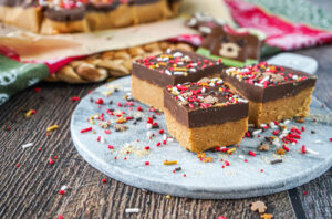 Three Chocolate Peanut Butter Bars on a marble board with sprinkles and ground graham crackers.