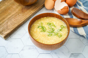 Egg Drop Soup in a brown bowl with egg shells in background.