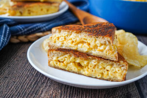 Two slices Grilled Mac and Cheese Sandwich on a plate with chips.
