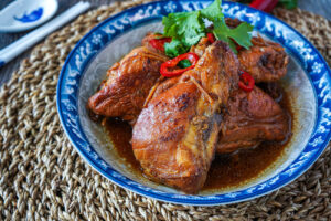 Gà Xào Gừng (Braised Chicken in Ginger) in a blue and gray bowl with chili slices and cilantro.