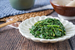 Japanese Kale with Sesame Dressing on a light green plate next to chopsticks.