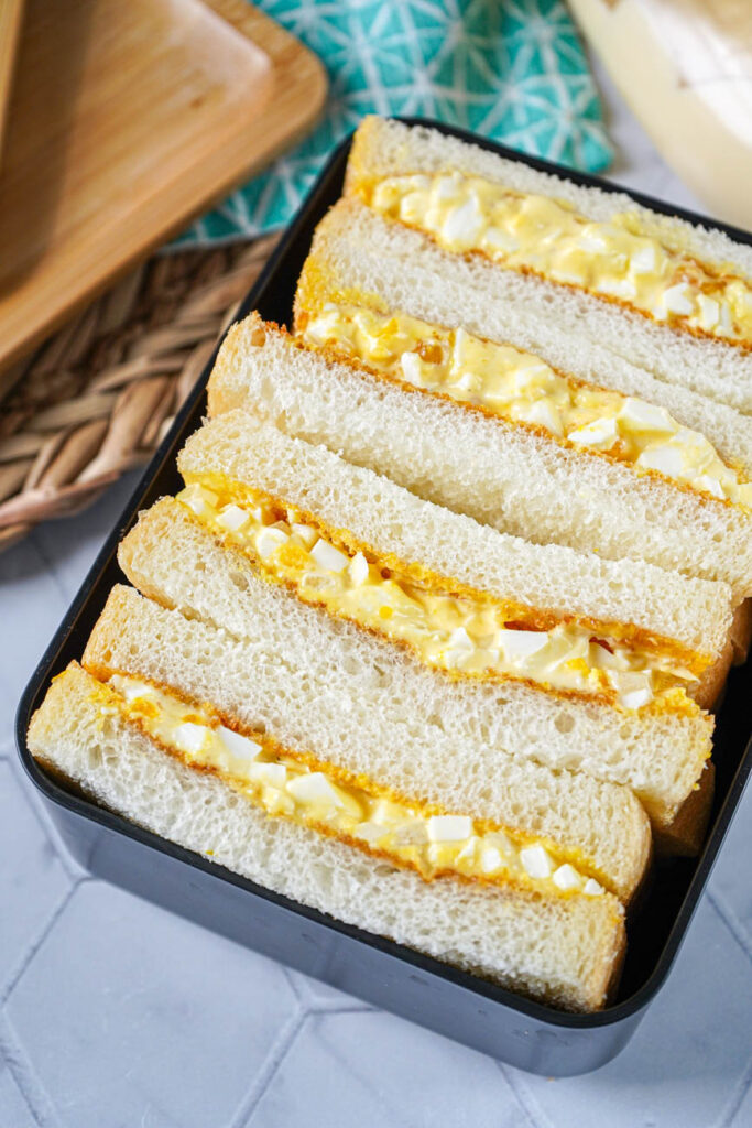 Four slices of Tamago Sando (Egg Salad Sandwich) in a bento box.