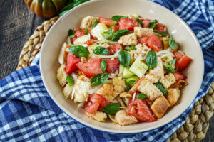 Panzanella (Tuscan Bread Salad) in a large bowl with fresh basil leaves.