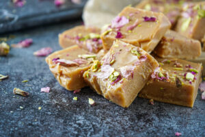 Squares of Saffron Black Cardamom Fudge topped with rose petals and pistachios.