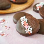 Double Chocolate Sablés dipped in dark chocolate with two coated in heart sprinkles.
