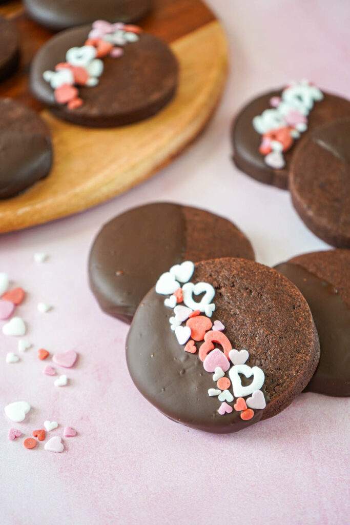 Close up of Double Chocolate Sablés half dipped in dark chocolate and covered in heart sprinkles.