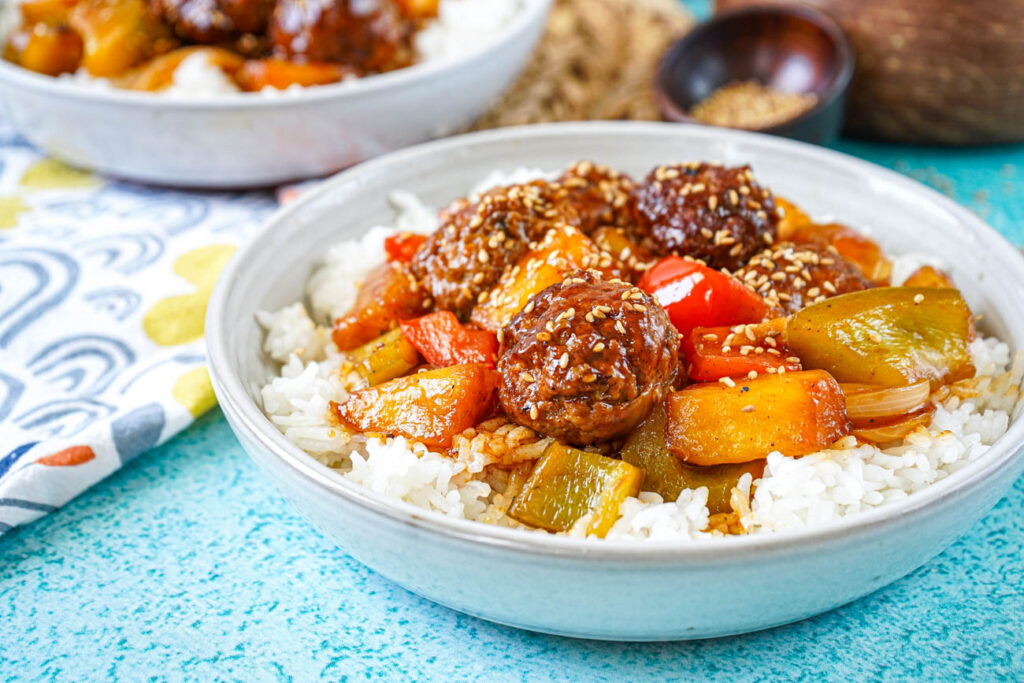 Sweet and Sour Pineapple Meatballs over rice in two bowls.