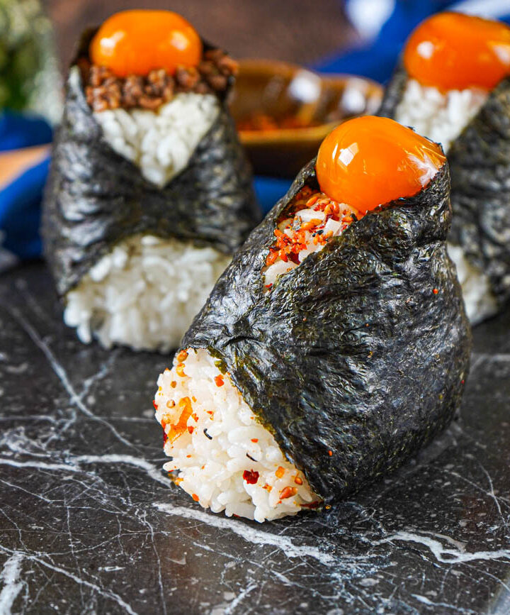 Three Egg Yolk Onigiri on a marble board.