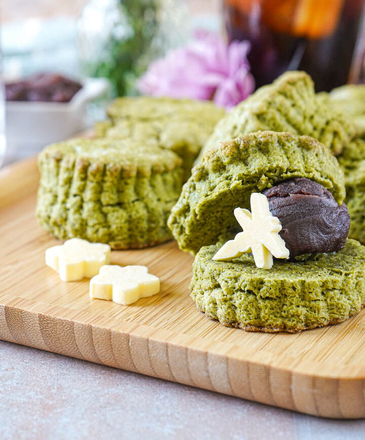 Matcha Scones on a wooden board with one cut in half and filled with red bean paste and a dragonfly-shaped piece of butter.