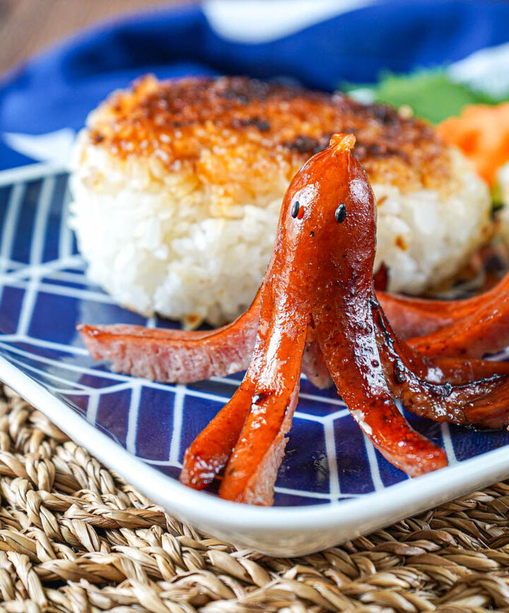 Two Octopus-Shaped Hot Dogs on a plate with grilled rice balls.