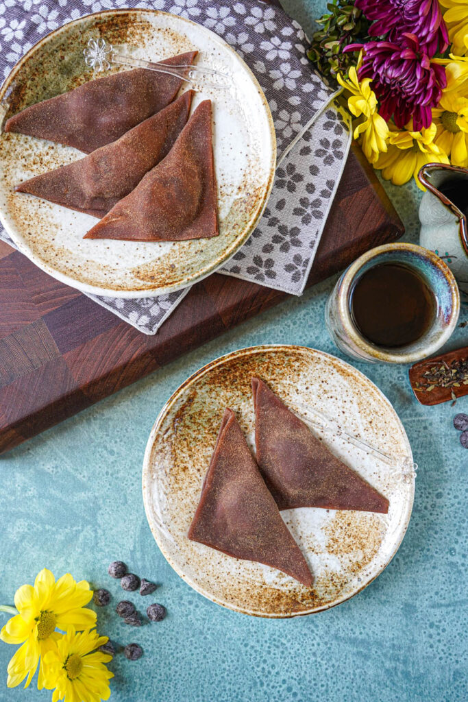 Aerial view of Chocolate Nama Yatsuhashi on two plates next to a cup of tea.