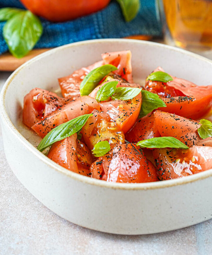 Tomato and Lapsang Souchong Salad in a bowl with basil leaves.