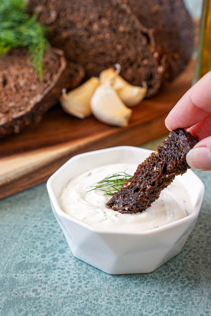 Dipping a piece of Baltic Fried Bread into a bowl of sour cream.