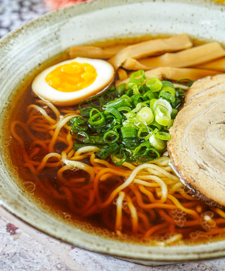 Fastest-Ever Homemade Shoyu Ramen in a bowl with half an egg, green onions, and pork slice.