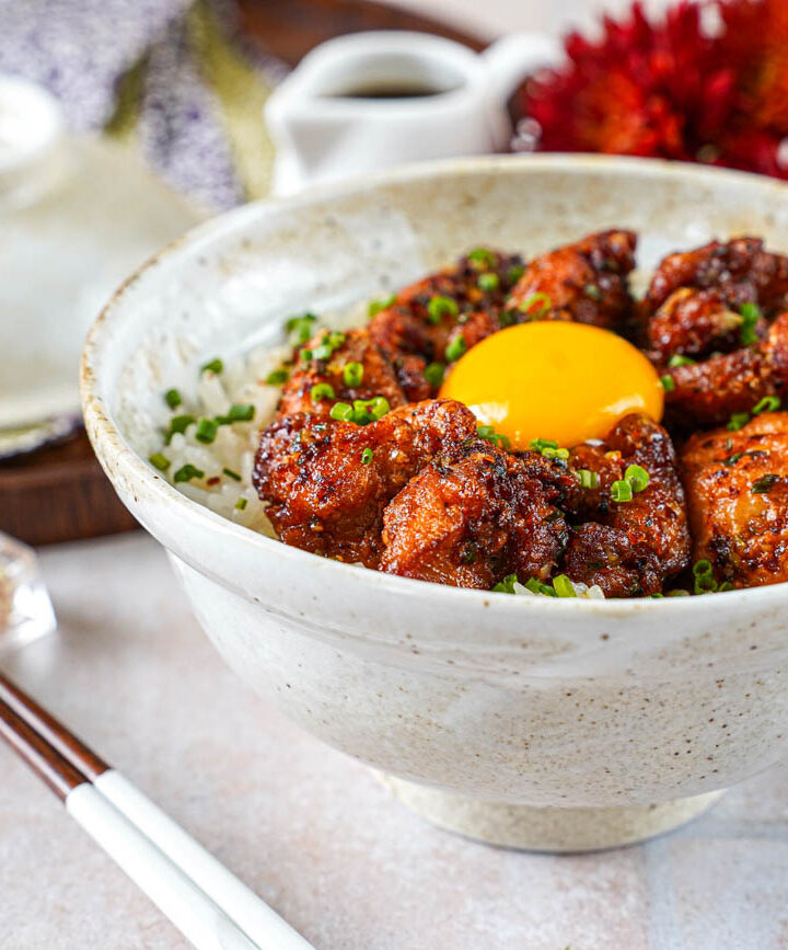 Garlic Butter Crispy Chicken Rice in a bowl next to chopsticks and red flowers.