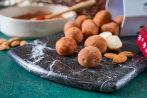 Marzipankartoffeln (Marzipan Potatoes) on a marble board next to almonds.