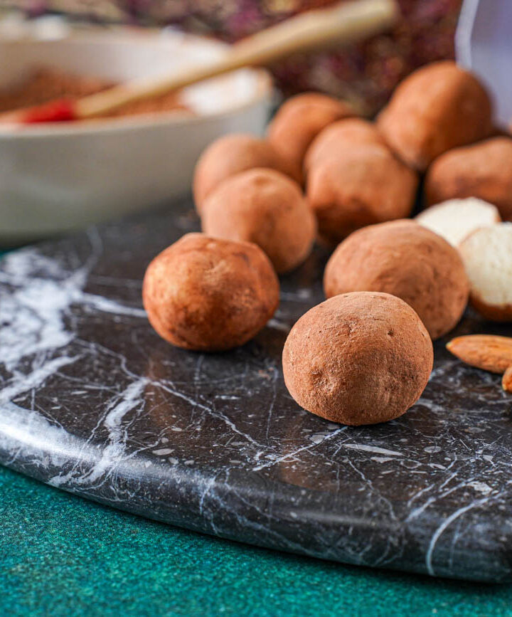 Marzipankartoffeln (Marzipan Potatoes) on a marble board next to almonds.
