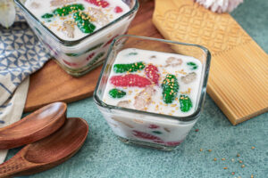 Krong Krang Nam Kati in two glass bowls next to two wooden spoons.