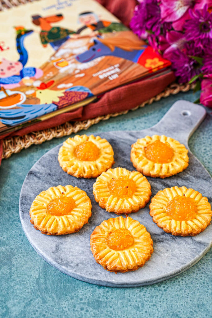 Six Pineapple Tarts on a marble board next to Monkey's Sweet Surprise book.