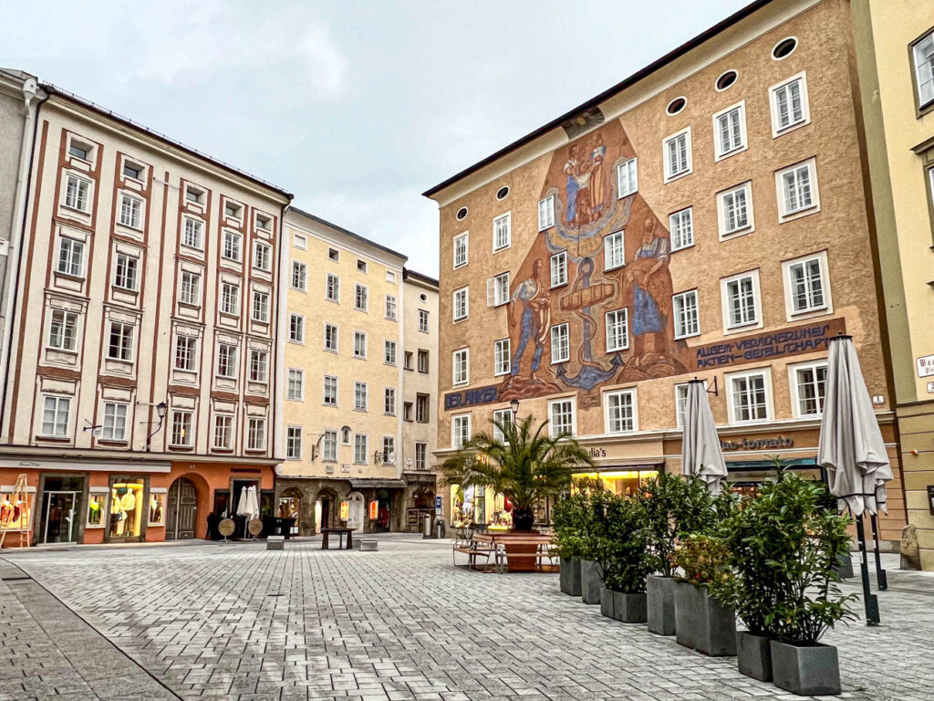 Tan buildings in Salzburg with plants in square gray planters.
