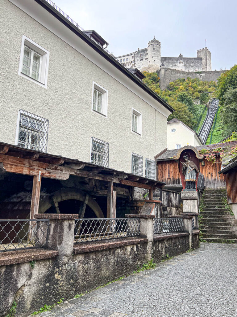 Wooden mill with funicular and fortress in background.