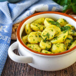 Petersilienerdäpfel (Parsley Potatoes) in a white bowl next to a blue towel.