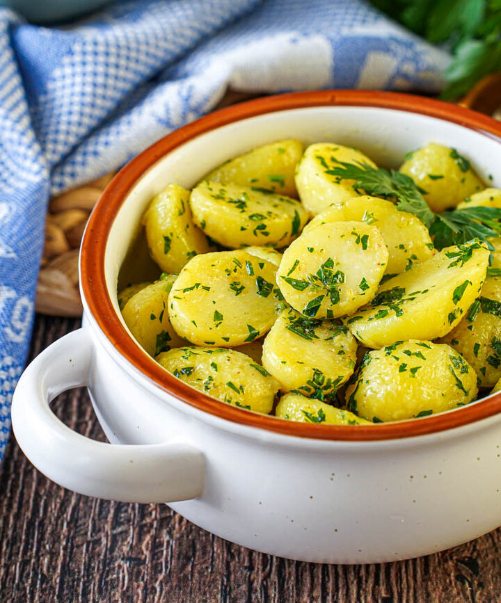 Petersilienerdäpfel (Parsley Potatoes) in a white bowl next to a blue towel.